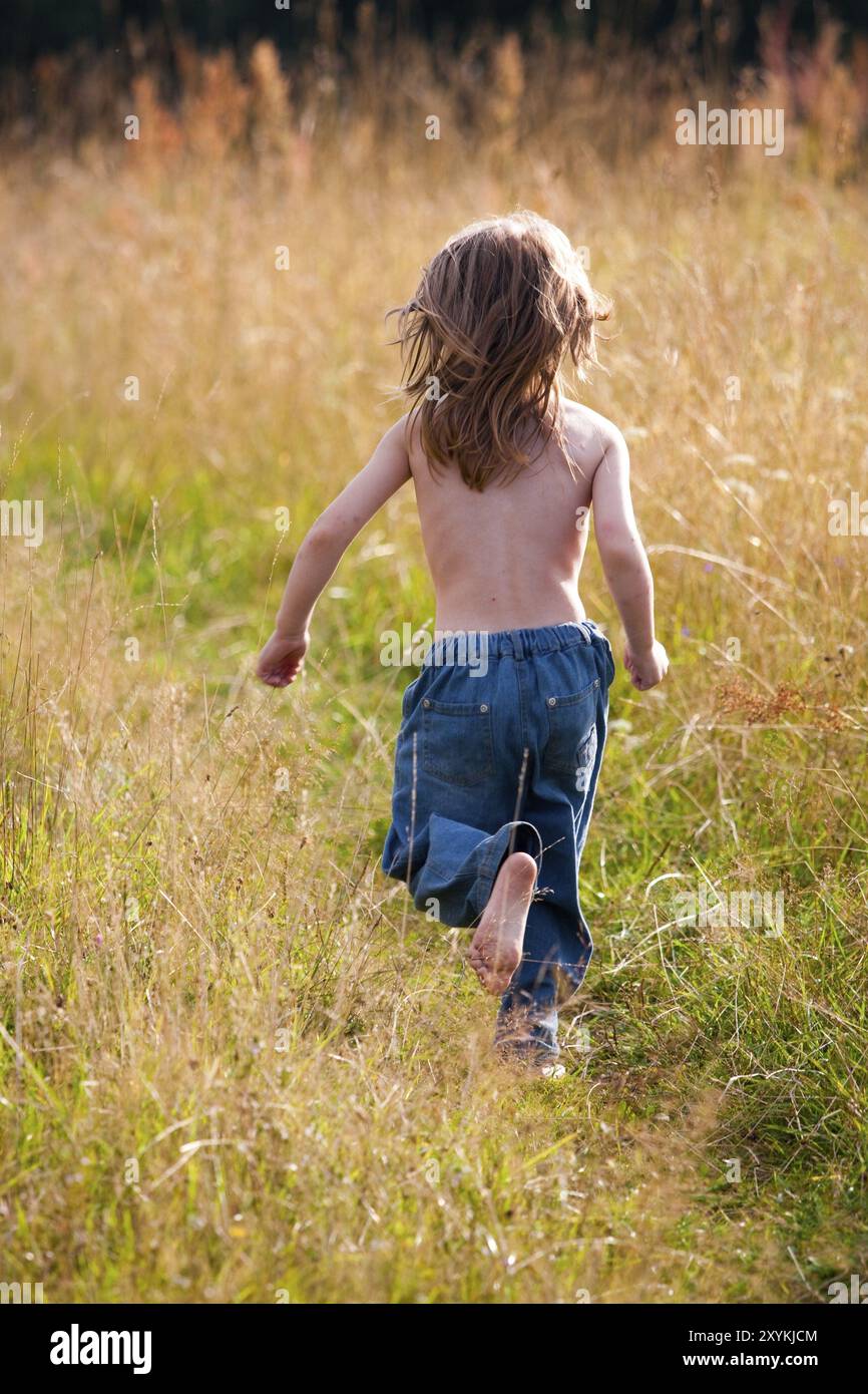 Ein Kind, das auf einem Pfad im Feld läuft. Sonniges Foto Stockfoto