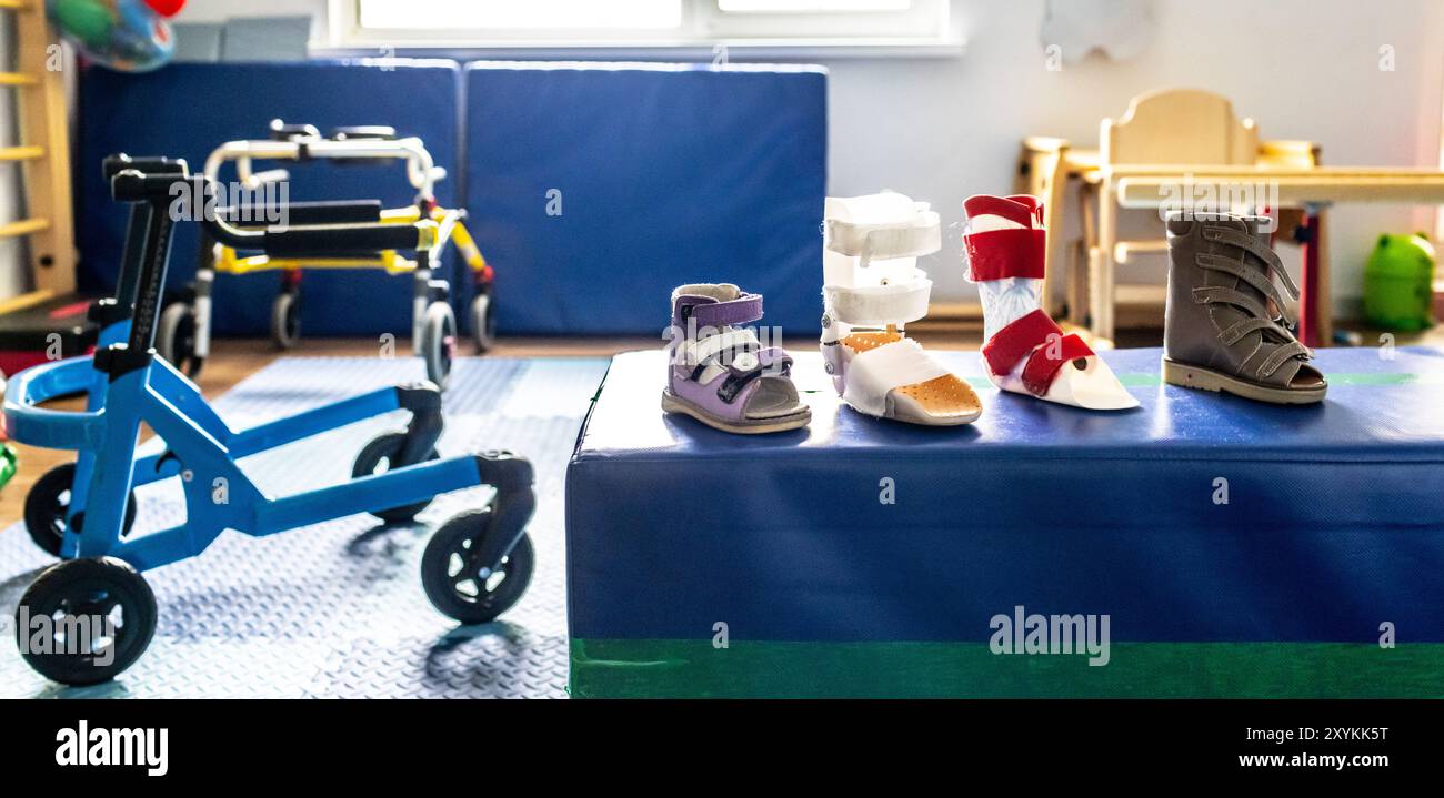 Unterstützende Schuhe und Mobilitätshilfen werden für die körperliche Rehabilitation von Kindern in einem einladenden Therapiebereich organisiert Stockfoto