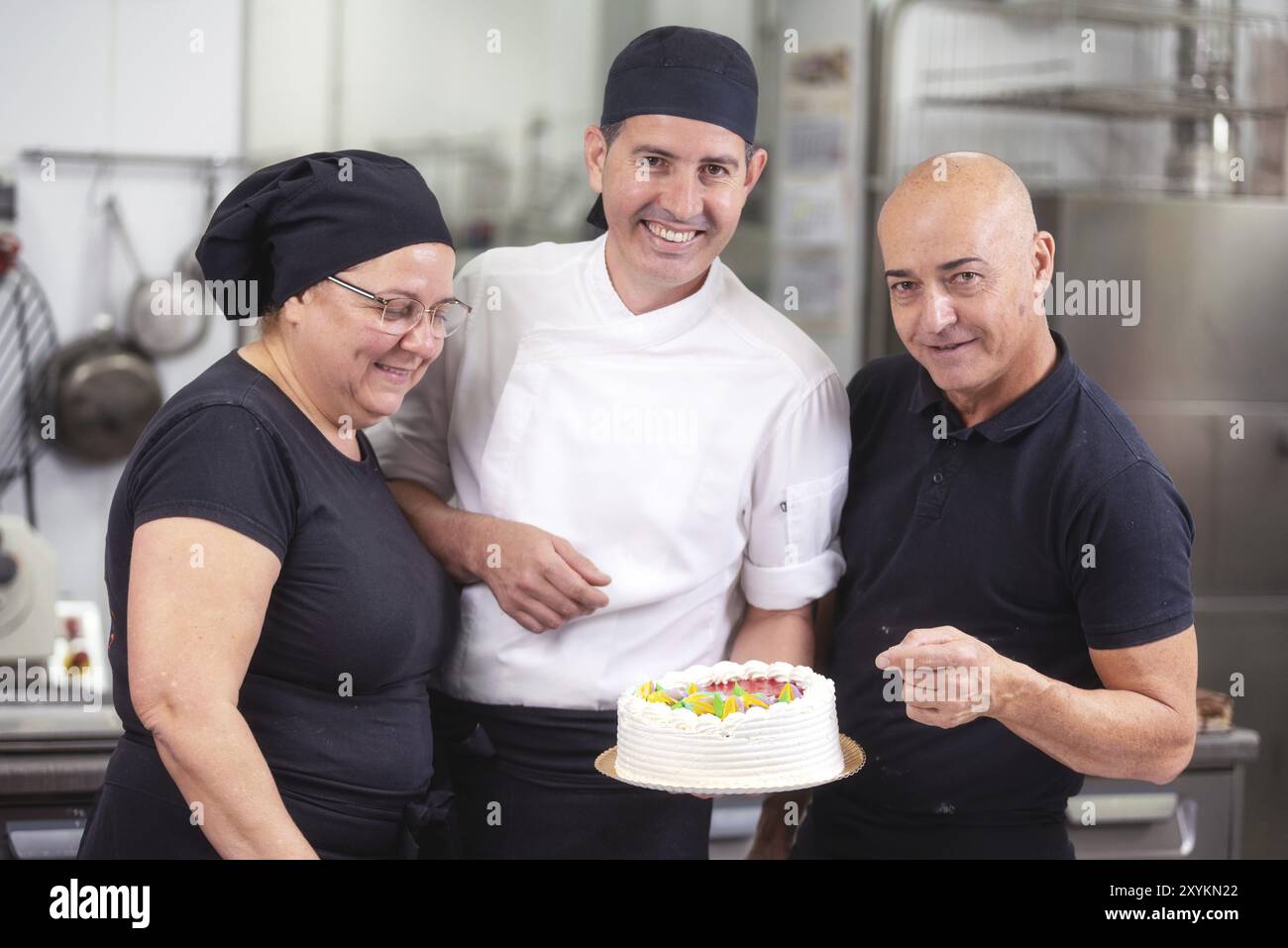 Das lächelnde Konditorteam zeigt einen Kuchen Stockfoto