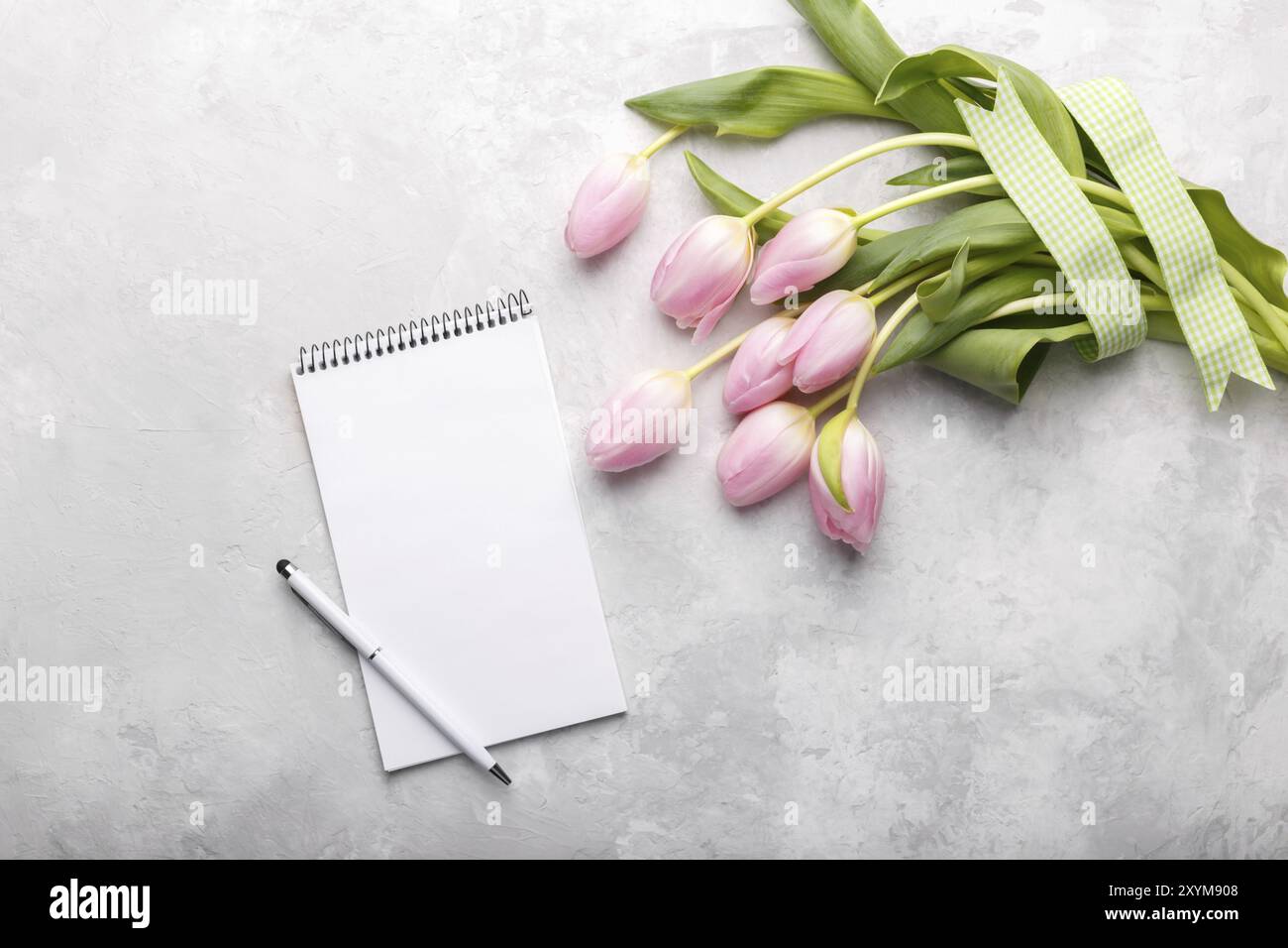 Leere Notepad und Bouquet von rosa Tulpe Blumen am grauen Stein table top Aussicht in flachen offen legen. Weibliche desk top Stockfoto