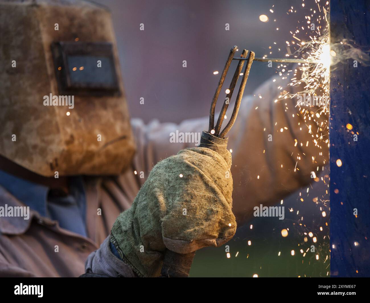 Schwere Industrie Schweißgerät Arbeiter in Schutzmaske Hand arc Schweißbrenner arbeiten auf Metall Bau Stockfoto