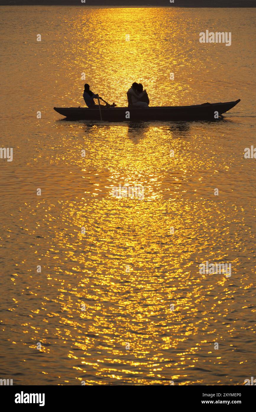 Silhouetten indischer Touristen machen eine Ruderbootfahrt bei Sonnenuntergang auf dem Ganges in Varanasi, Indien, Asien Stockfoto