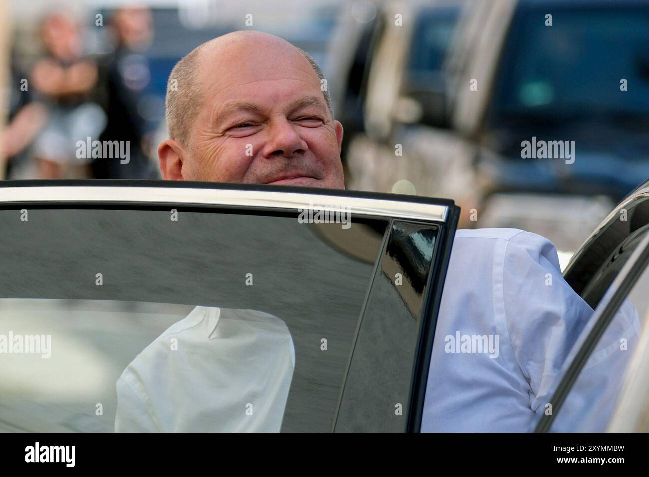 Freiberg, Deutschland. 30. August 2024. Bundeskanzler Olaf Scholz (SPD) besucht die Bergbaubehörde Freiberg, die für die Förderung und Regulierung des Bergbaus einschließlich der Lithiumgewinnung im Erzgebirge zuständig ist, und lächelt, während er bei seinem Fahrzeug steht. Quelle: Sebastian Willnow/AP Pool/dpa/Alamy Live News Stockfoto