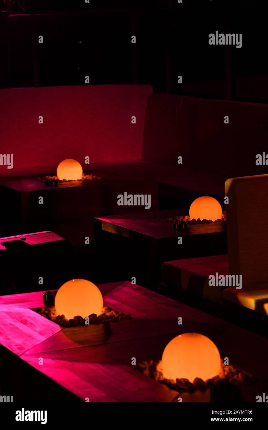Zickzack Glow: Orangene Glühbirnen als Tischdekoration im Nachtleben-Ambiente. Stockfoto