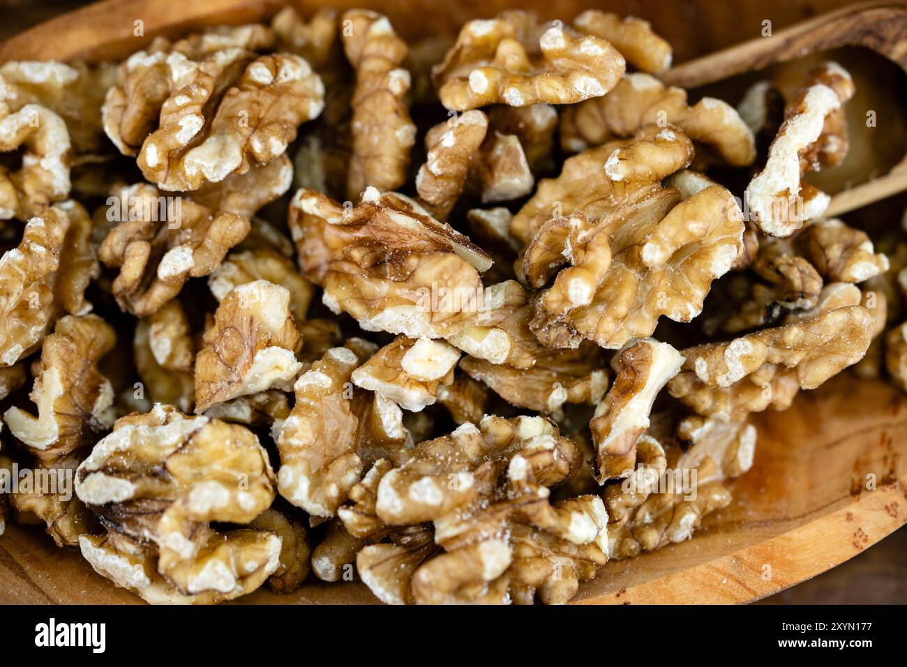 Walnuss (Juglans regia), gerissene Walnüsse mit einer Holzschaufel auf einem Holzteller Stockfoto