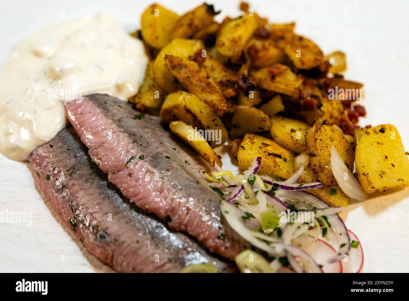 Matjes mit Remoulade, Zwiebeln und gebratenen Kartoffeln Stockfoto