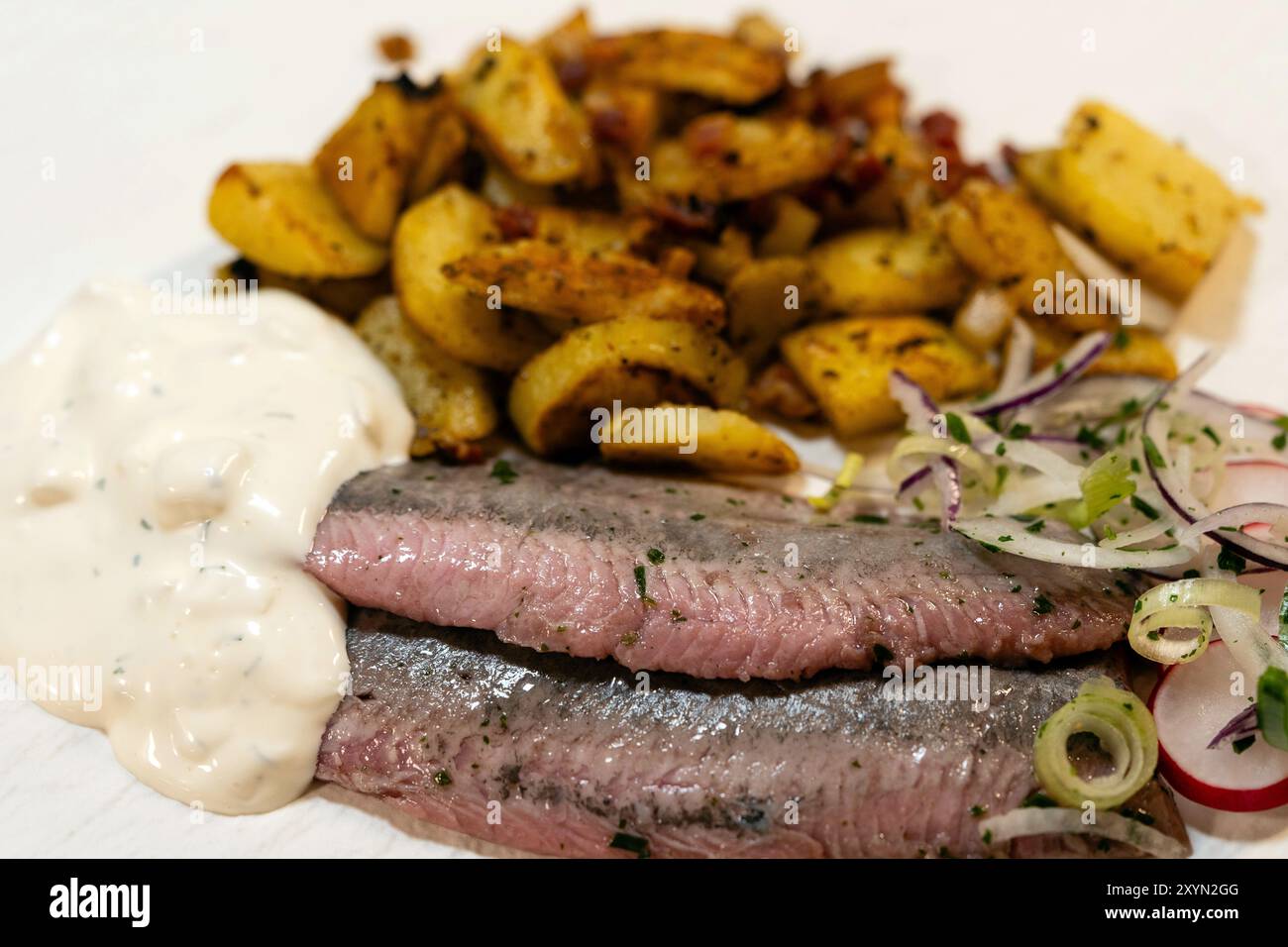 Matjes mit Remoulade, Zwiebeln und gebratenen Kartoffeln Stockfoto