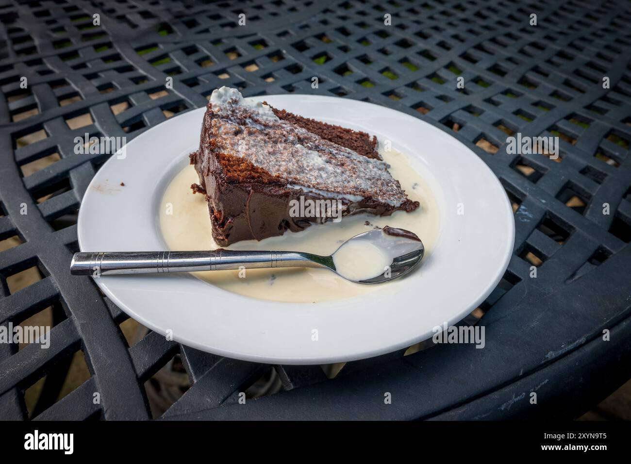 Ein Stück Schokoladenkuchen tropft in Sahne auf einem weißen Teller. Stockfoto