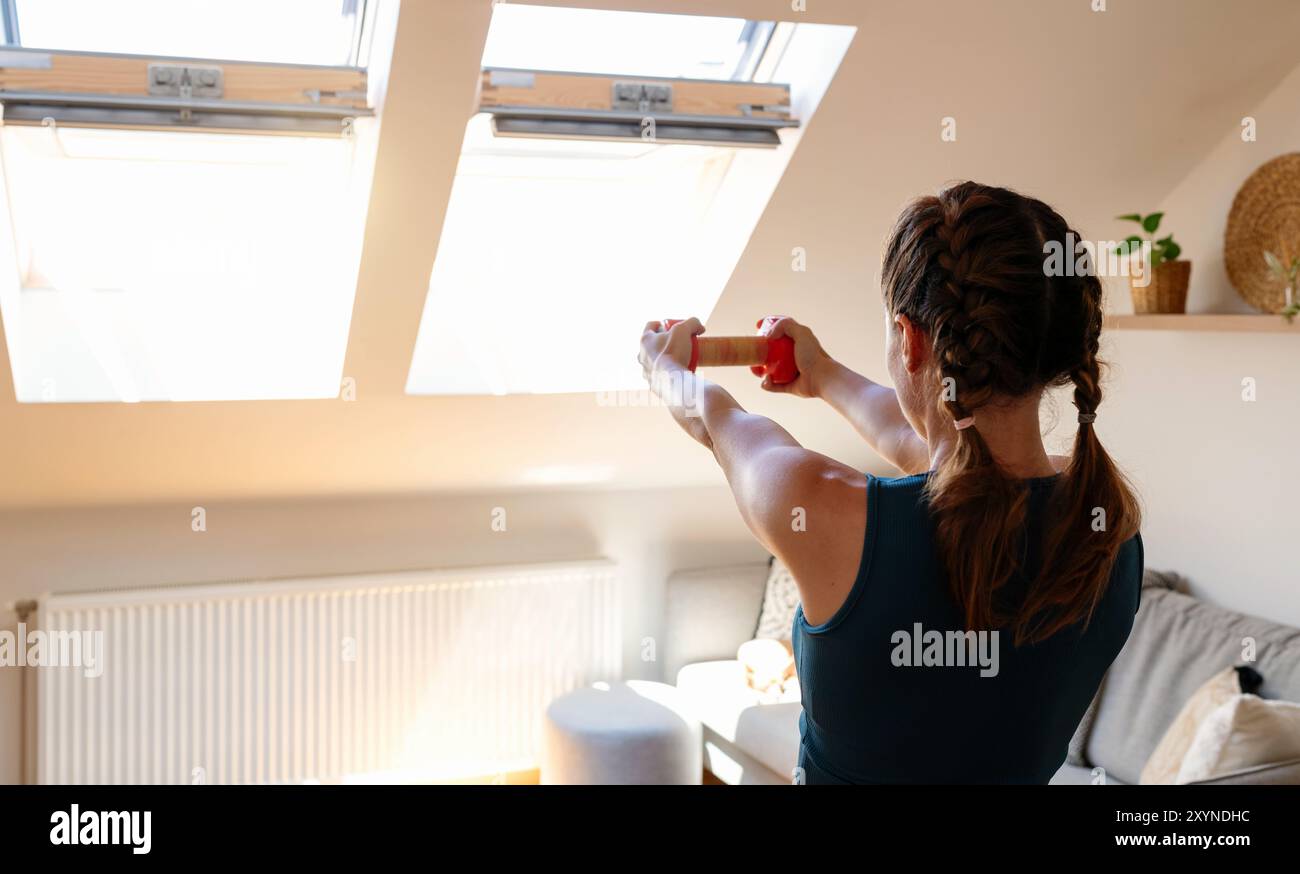 Sportliche Frau mit Kurzhantel beim Heimtraining. Stockfoto
