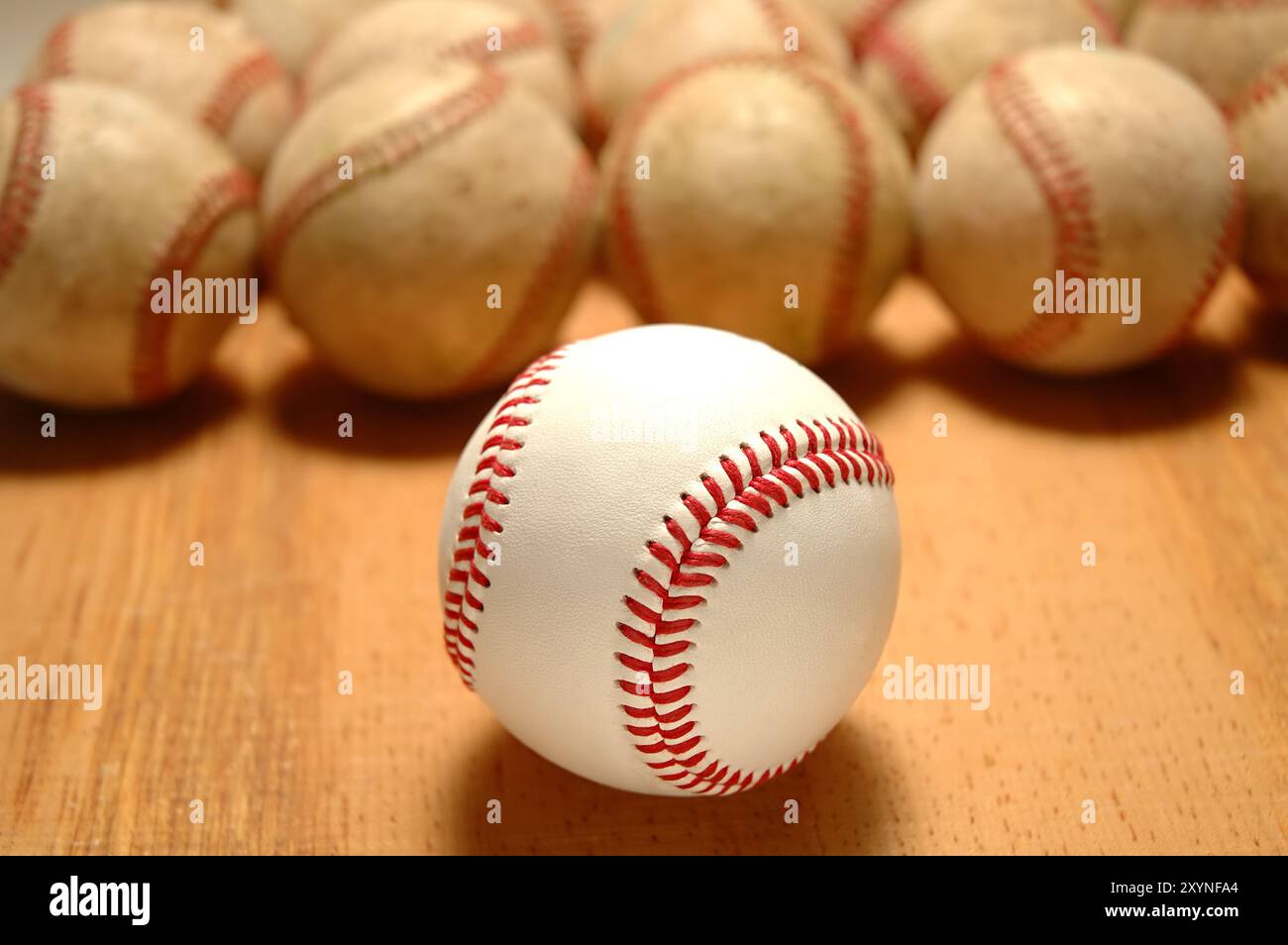 Nahaufnahme eines neuen Baseballs vor einer Reihe alter Use Balls, Fokus auf den vorderen Ball. Stockfoto