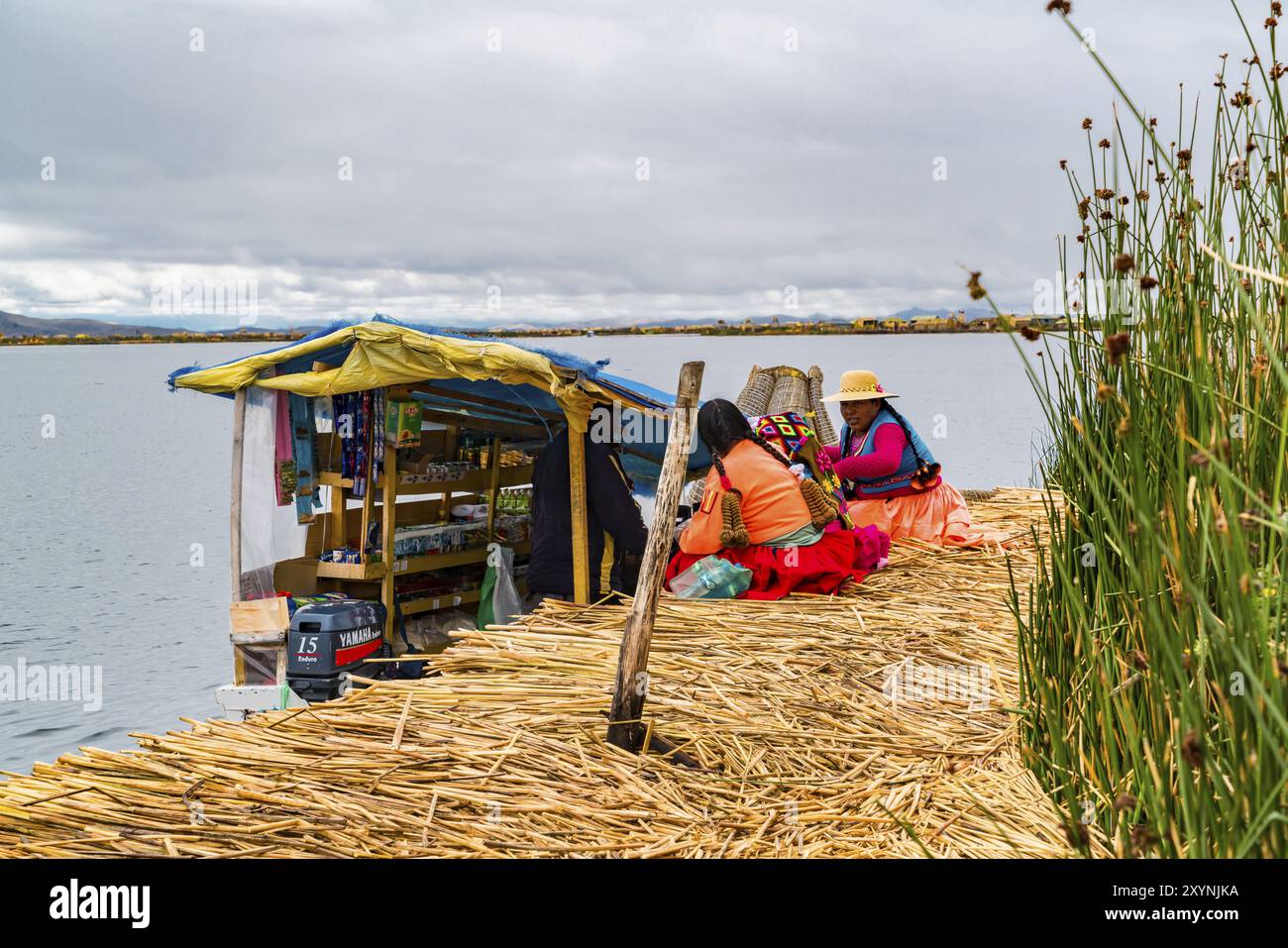 PUNO, PERU, 1. FEBRUAR 2016: Uru-Frau, die traditionelle Tücher trägt und Essen und notwendige Dinge auf einem Bootsmarkt auf der schwimmenden Insel Uros auf Lak kauft Stockfoto