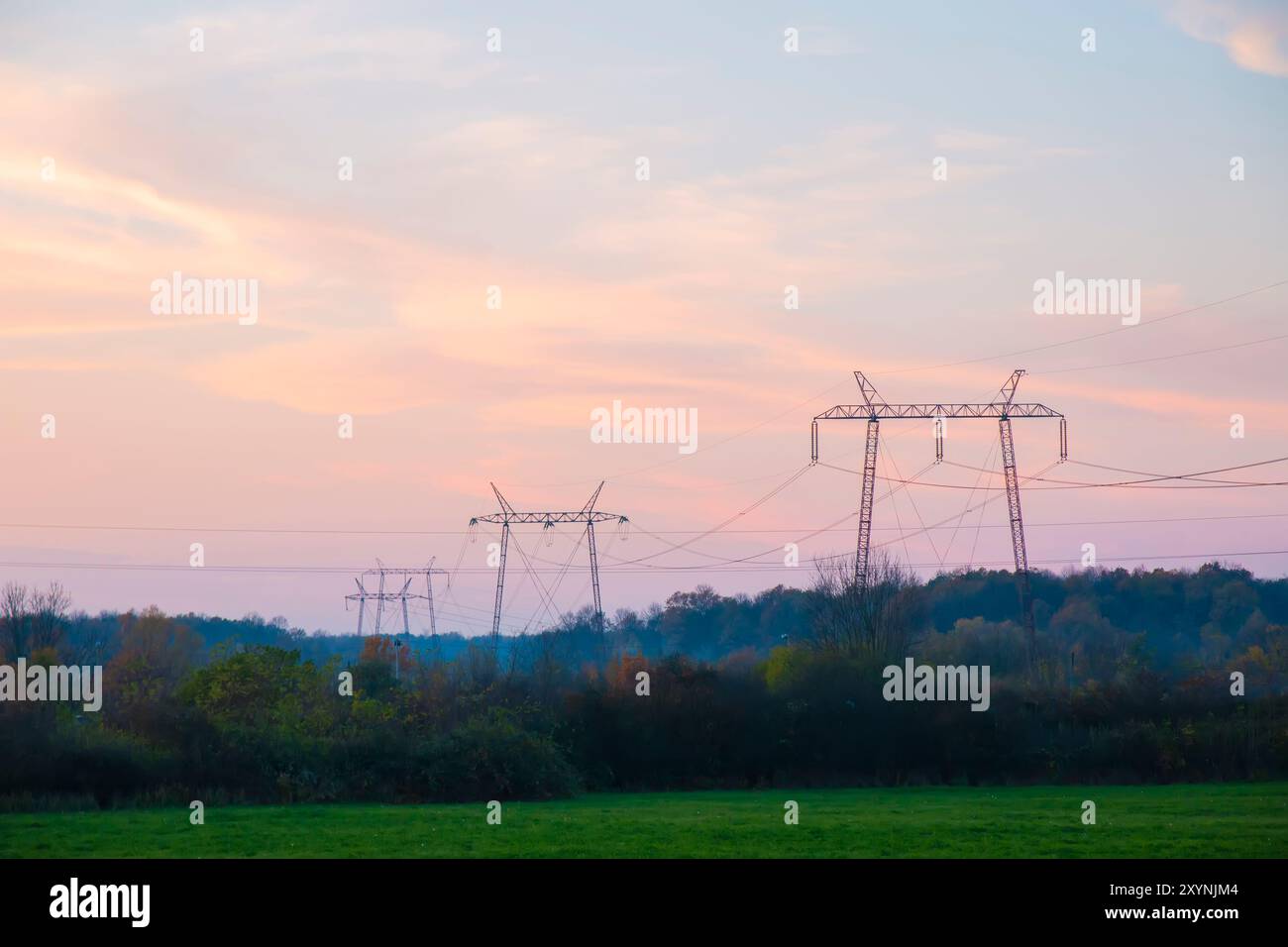 Hochspannungsleitungen bei Sonnenuntergang. In Zukunft - Elektrizitätsknappheit. Wegen der hohen Preise haben verzweifelte Menschen kein Geld für Strom Stockfoto