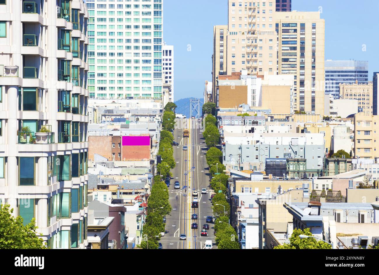 Fernblick über die California Street mit der berühmten Cable Car und der Spitze der Bay Bridge zwischen Wohnhäusern an klaren, sonnigen Tagen in Sa Stockfoto