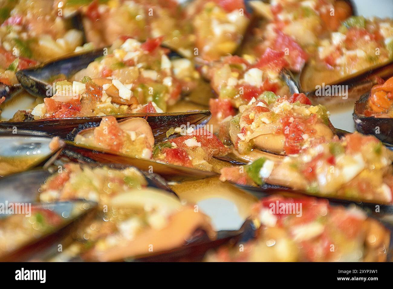 Nahaufnahme der lebendigen Details von Muscheln, serviert mit einem farbenfrohen Vinaigrette-Dressing. Jede Muschelschale wird großzügig mit einer Mischung aus gehacktem t belegt Stockfoto