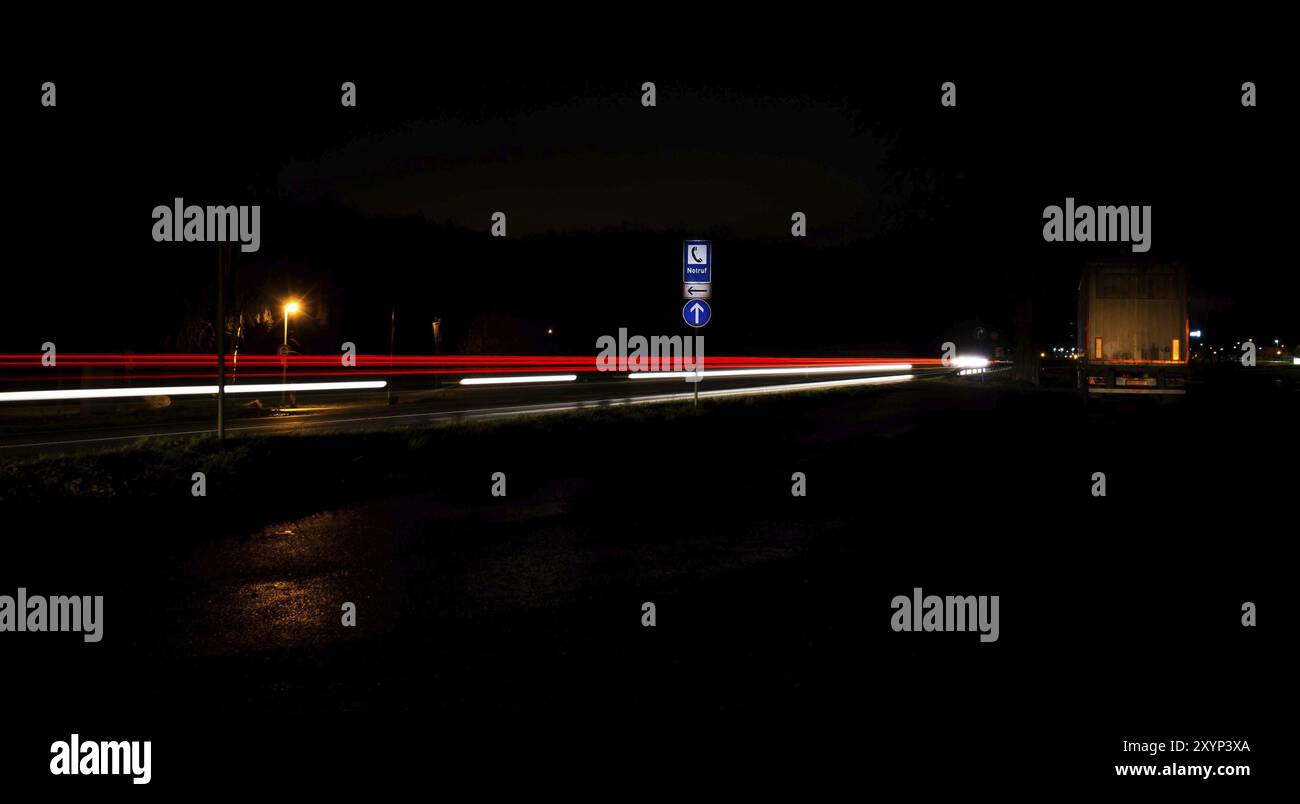 Autos, die nachts auf einer befahrenen Autobahn an einem Notstoppschild vorbeifahren Stockfoto