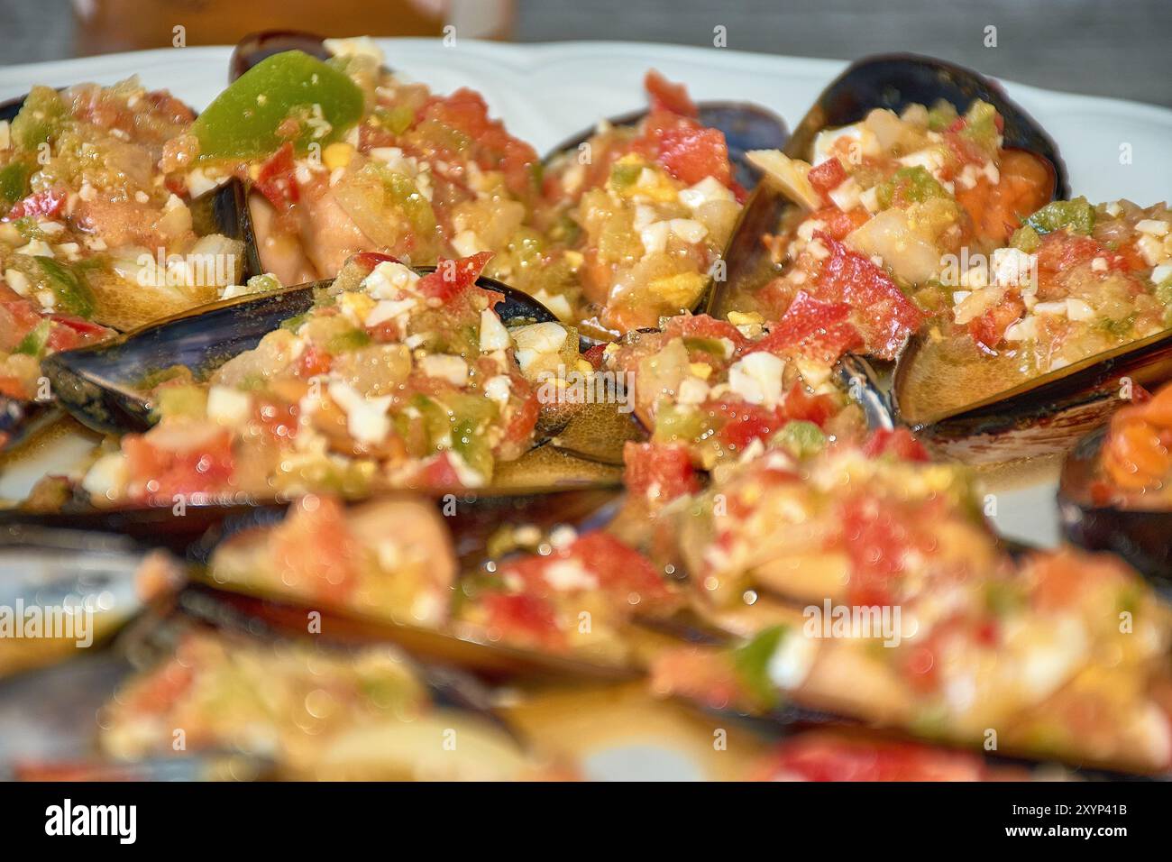Nahaufnahme der lebendigen Details von Muscheln, serviert mit einem farbenfrohen Vinaigrette-Dressing. Jede Muschelschale wird großzügig mit einer Mischung aus gehacktem t belegt Stockfoto