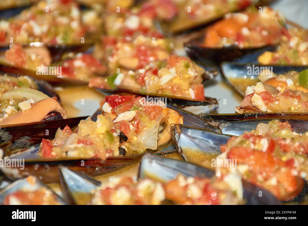 Nahaufnahme der lebendigen Details von Muscheln, serviert mit einem farbenfrohen Vinaigrette-Dressing. Jede Muschelschale wird großzügig mit einer Mischung aus gehacktem t belegt Stockfoto
