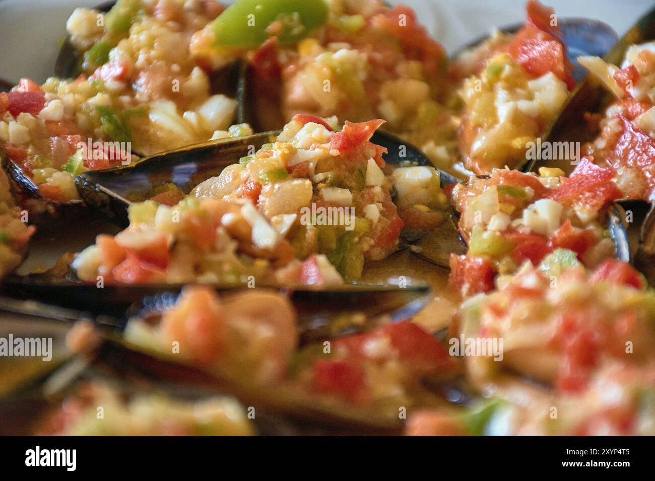 Nahaufnahme der lebendigen Details von Muscheln, serviert mit einem farbenfrohen Vinaigrette-Dressing. Jede Muschelschale wird großzügig mit einer Mischung aus gehacktem t belegt Stockfoto