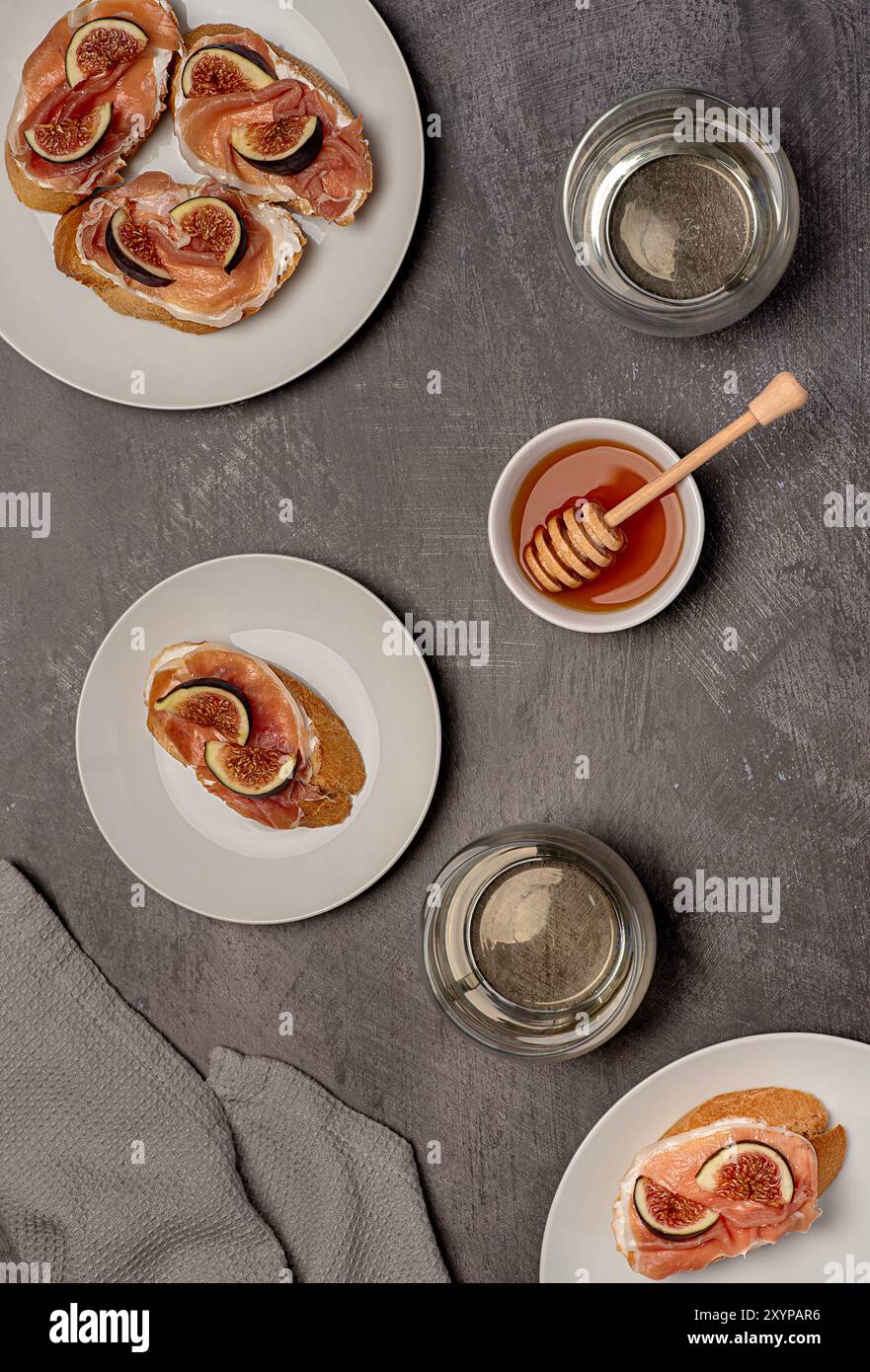 Lebensmittelfotografie von Bruschetta, Toast mit Weichkäse, Schinken und Feige, Honig, Weißwein, Getränk, Getränke, Frühstück, Hintergrund Stockfoto