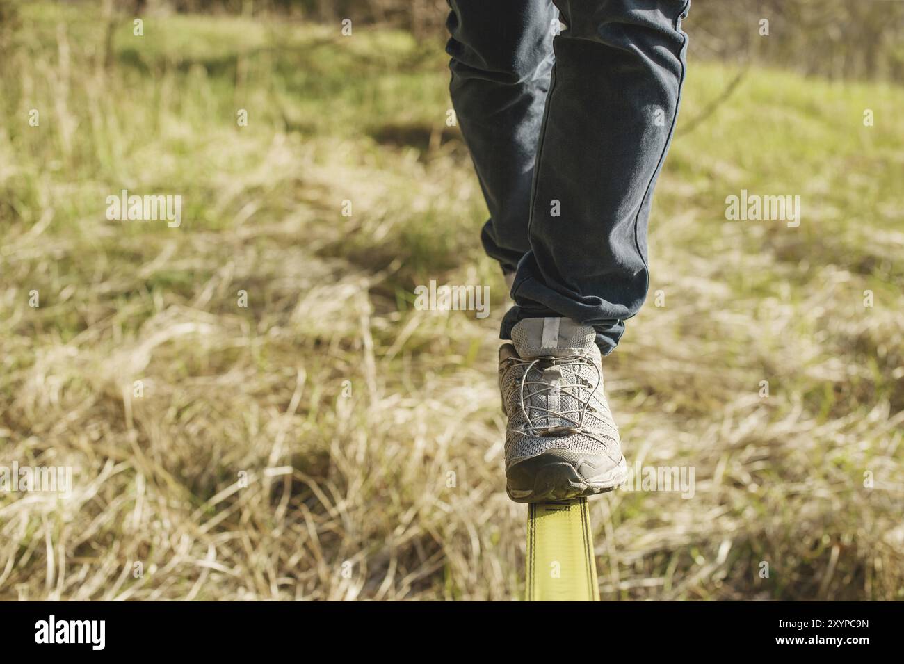 Close-up Slacklining ist eine Praxis des Balancierens, bei der üblicherweise Nylon- oder Polyestergewebe zwischen zwei Ankerpunkten verwendet werden. Menschen gehen Stockfoto