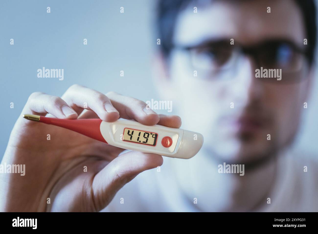 Mann hält eine rote fieber thermometer mit hohen Temperaturen in seiner Hand, verschwommene Gesicht Stockfoto