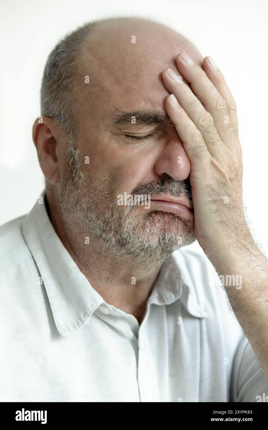 Der Mann bedeckt sein Gesicht mit einer Hand Stockfoto