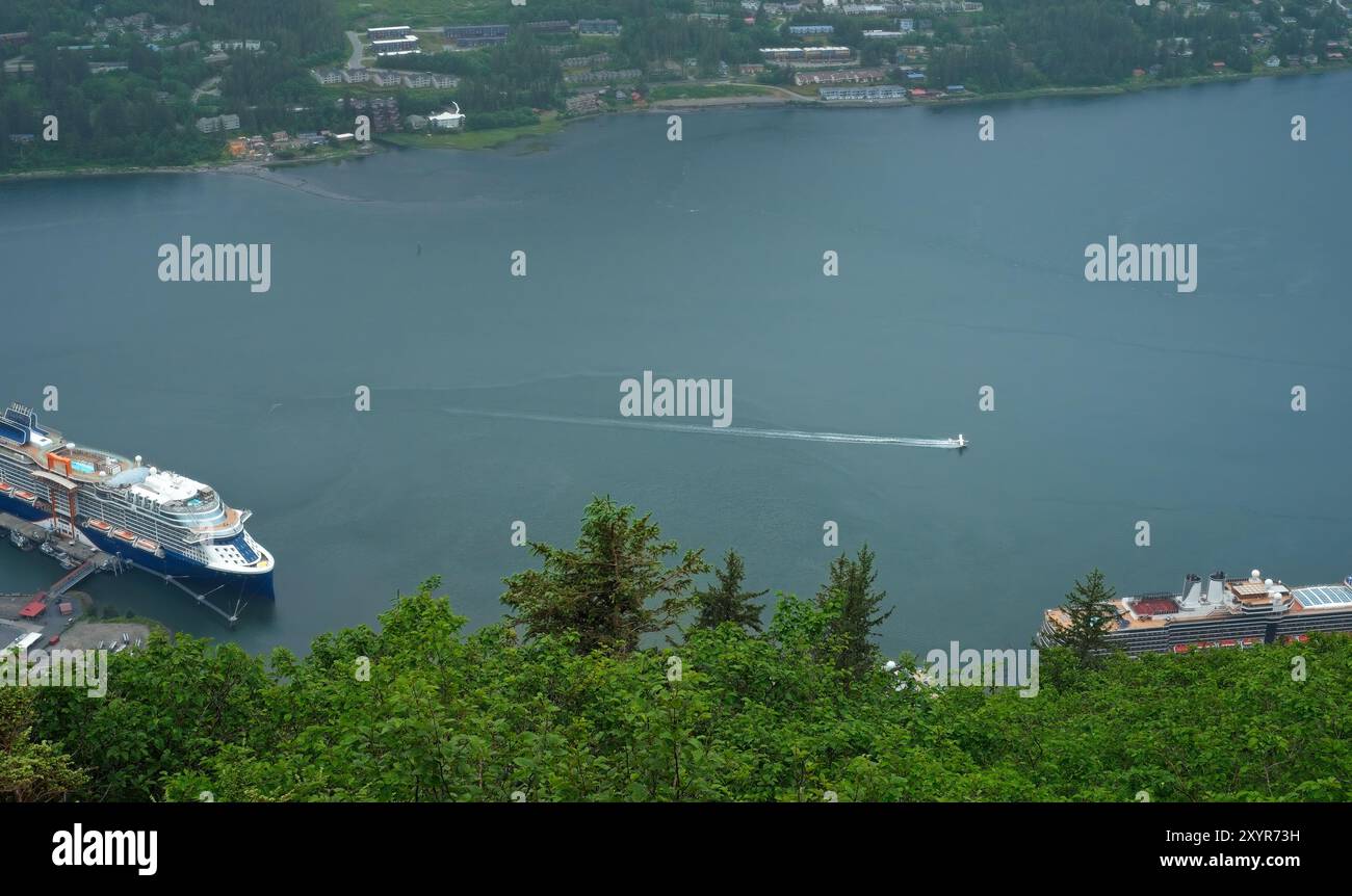 Ein kleines Wasserflugzeug landet im Gastineau Channel in Juneau, Alaska, mit Kreuzfahrtschiffen in der Nähe Stockfoto