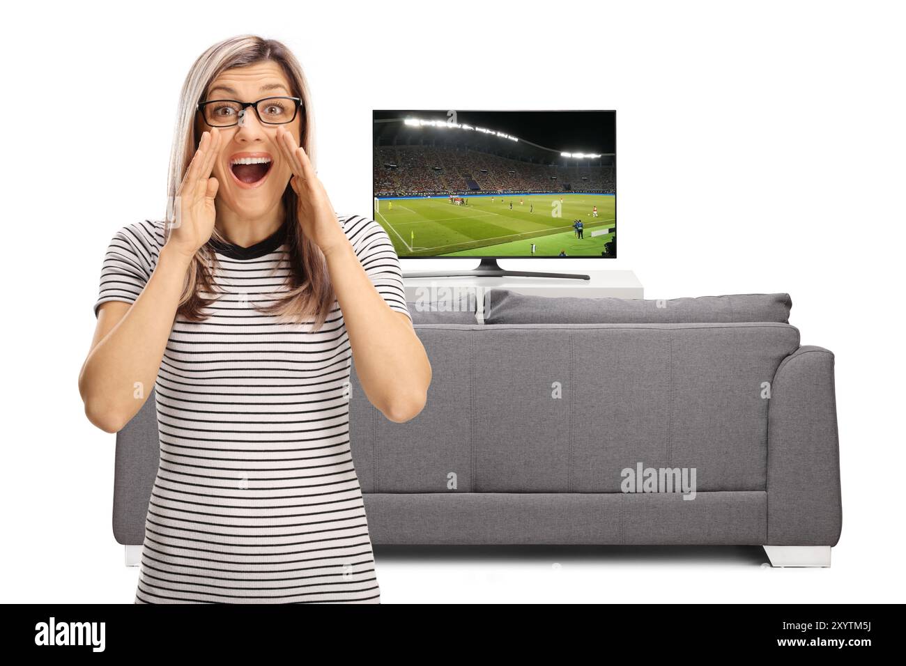 Blonde Frau, die ein Fußballspiel ansieht und vor dem fernseher und Sofa auf weißem Hintergrund schreien kann Stockfoto