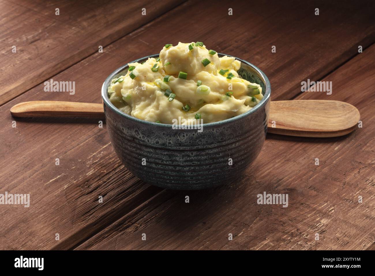 Pomme Püree, ein Foto von einer Schüssel Kartoffelpüree mit Kräutern auf einem dunklen Hintergrund im Landhausstil mit einem hölzernen Löffel und kopieren Raum Stockfoto