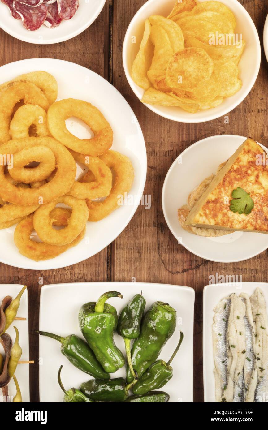 Spanische Tapas, eine Auswahl an Snacks. Tintenfischringe, Tortilla, Sardinen, padron Paprika, Top Shot auf einem dunklen Holzmöbeln im Landhausstil Hintergrund Stockfoto