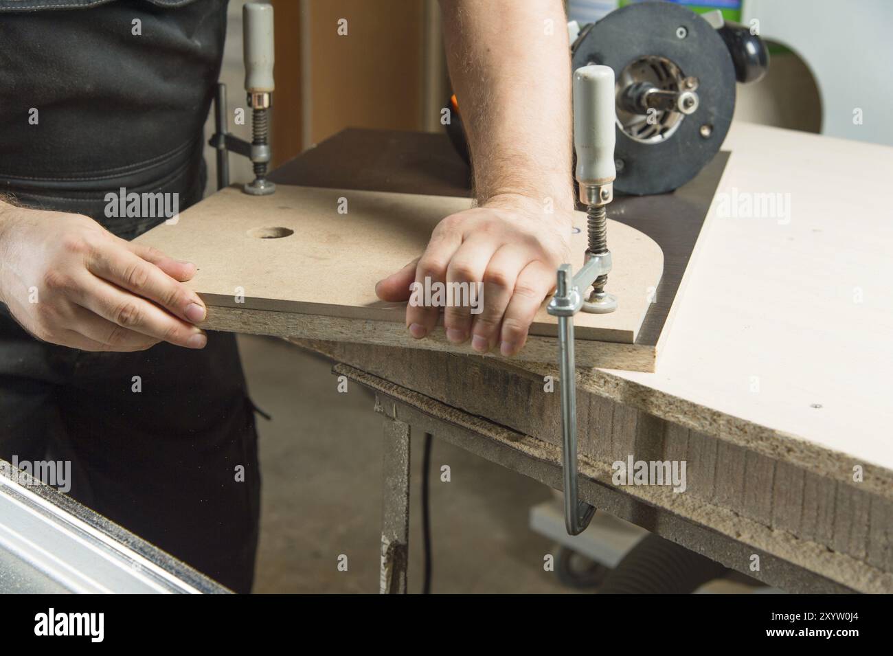 Close Up Master klemmt das Werkstück mit einer dvp-Klemme an der Werkbank und auf dem Hintergrund liegt der Handfräser von Carpentry Stockfoto