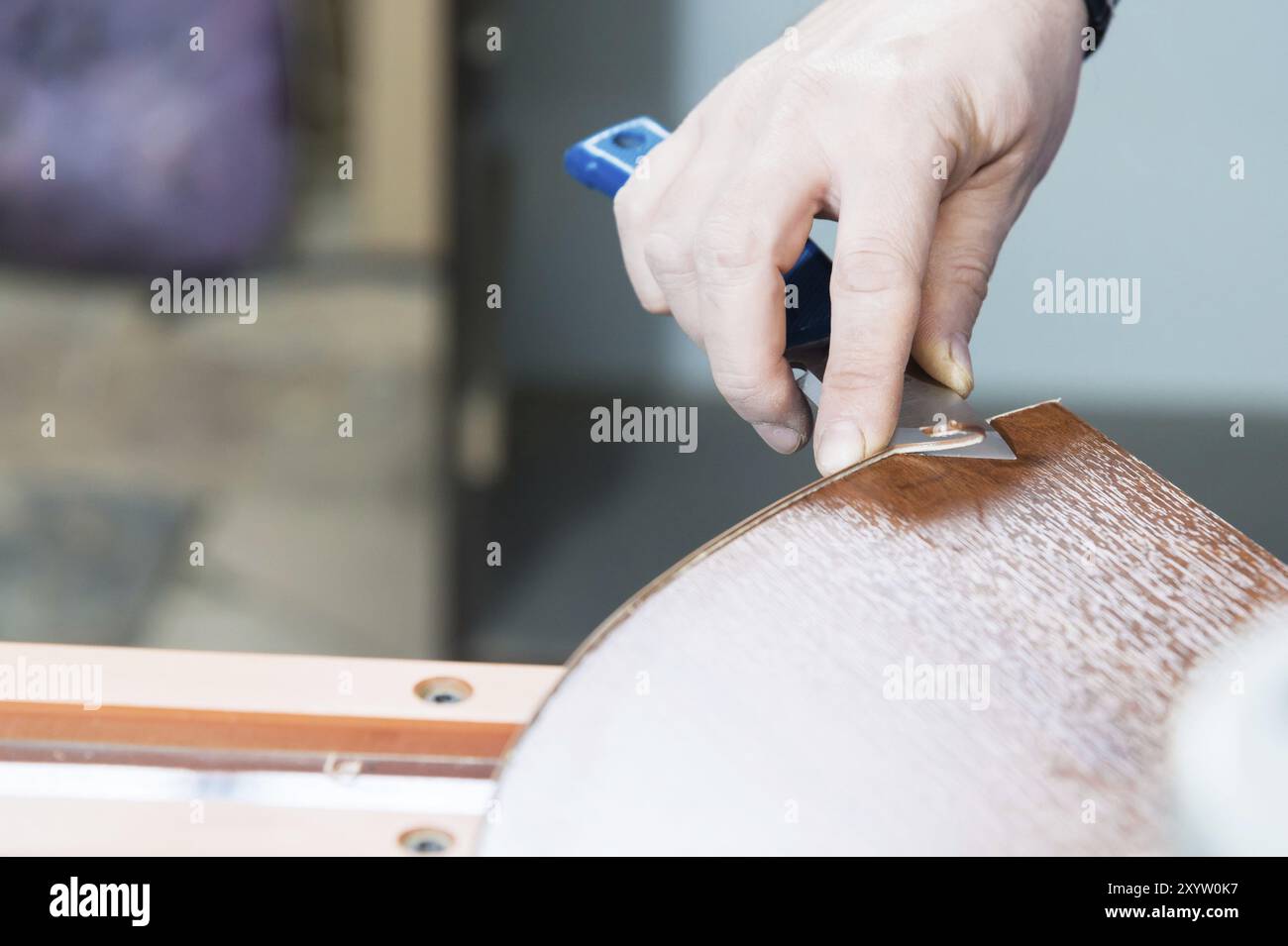 Eine Nahaufnahme der nicht gepflegten Hände des echten Zimmermanns rundet die Verarbeitung der Spanplattendetails der Möbel ab, indem sie die Kante abschneidet Stockfoto