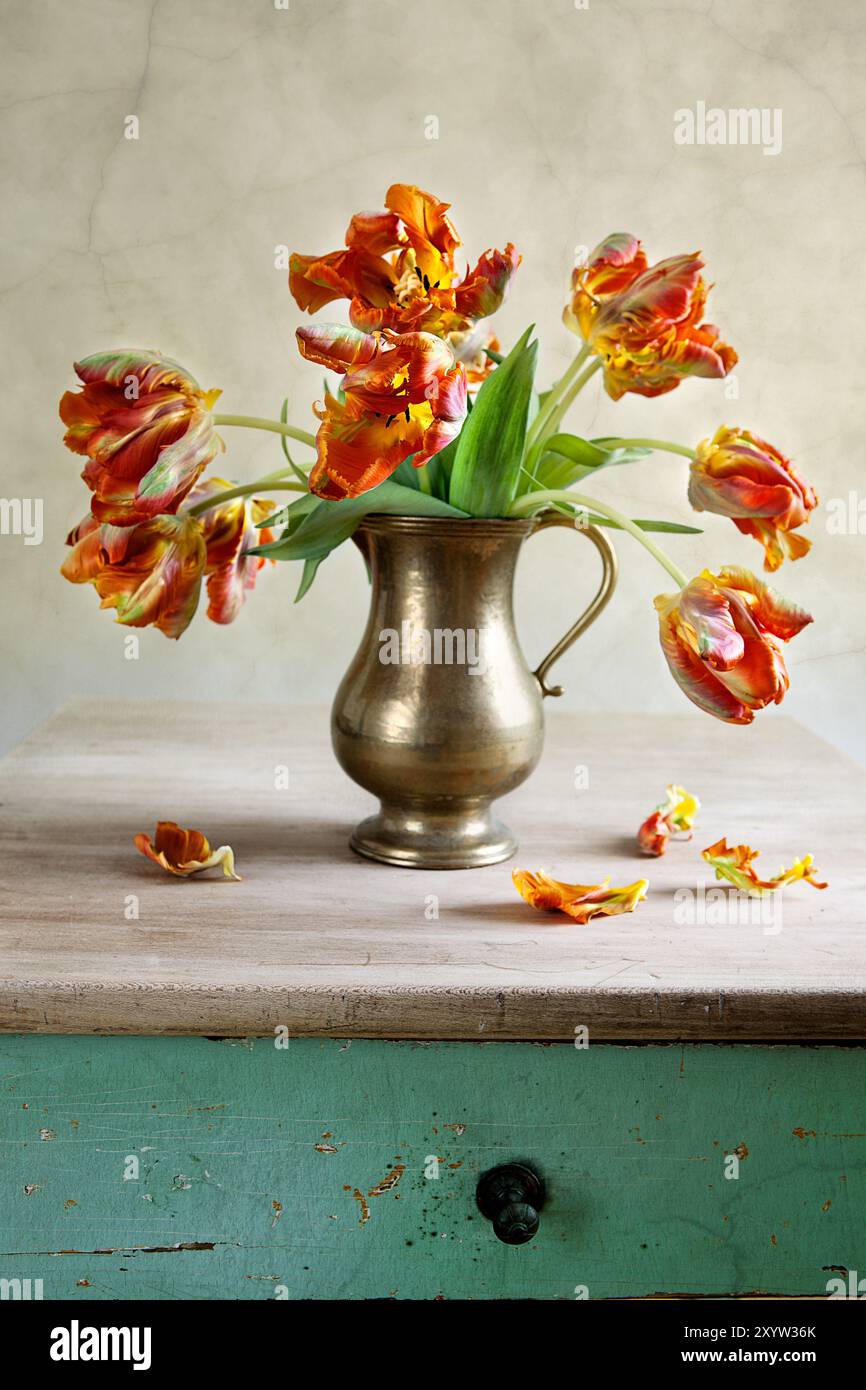 Dekoratives Stillleben mit Tulpen in antikem Metallgefäß auf Altem Tisch Stockfoto