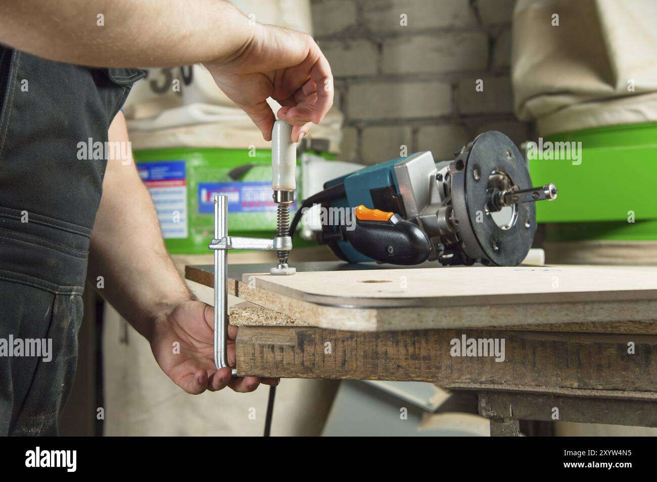 Close Up Master klemmt das Werkstück mit einer dvp-Klemme an der Werkbank und auf dem Hintergrund liegt der Handfräser von Carpentry Stockfoto