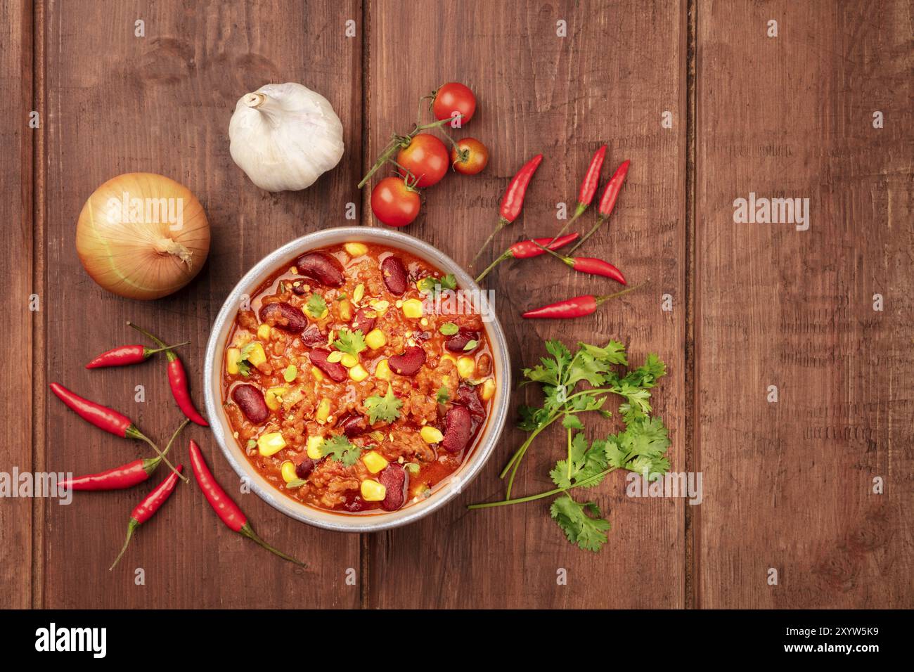 Chili con Carne, geschossen von oben auf einen dunklen Holzmöbeln im Landhausstil Hintergrund mit Zutaten und ein Platz für Text Stockfoto