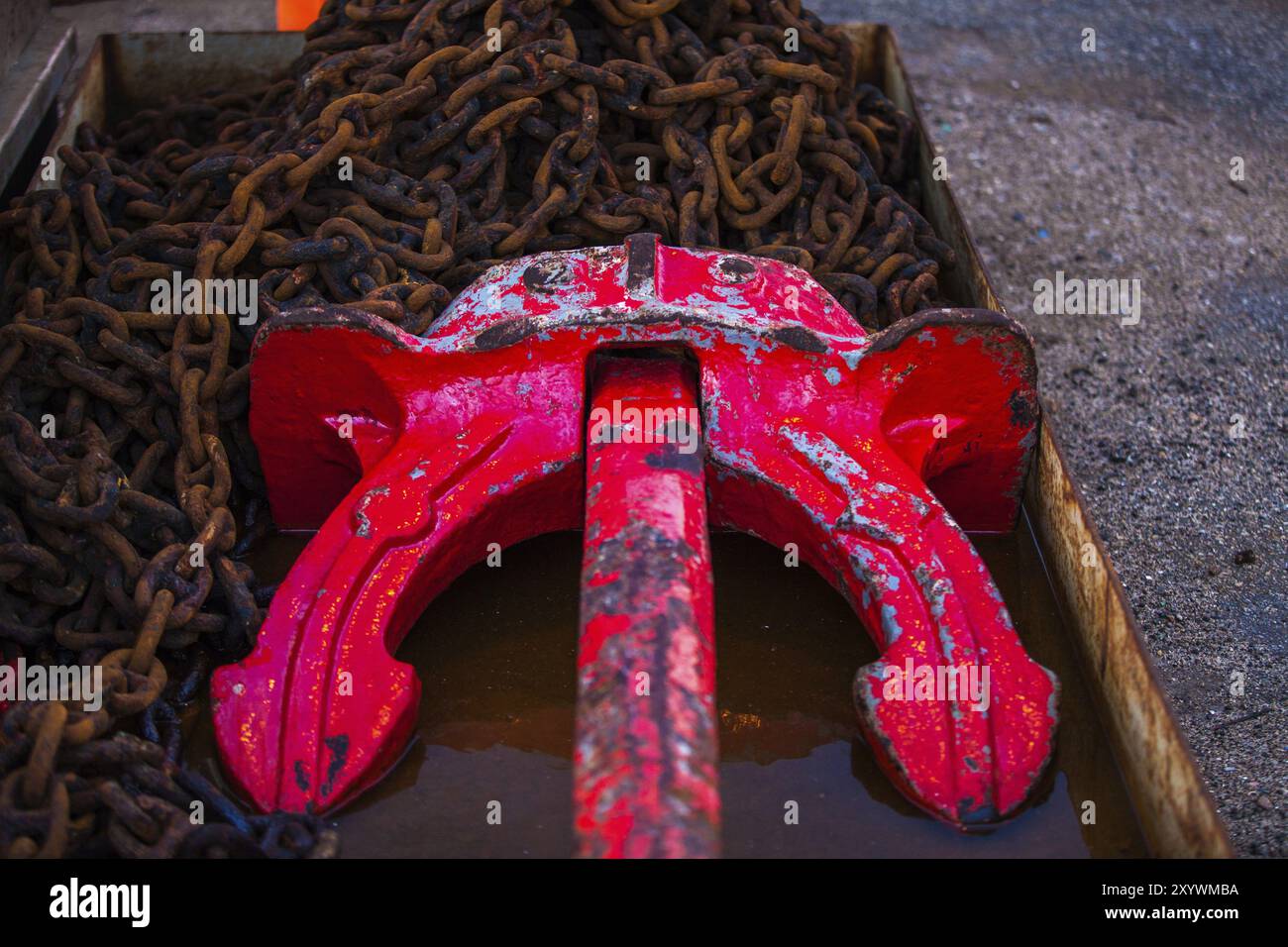 Roter rostiger Anker in einem Becken mit rostiger Eisenkette Stockfoto