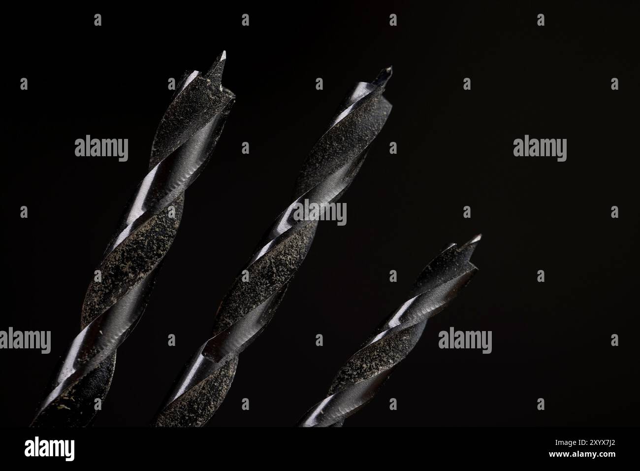 Metallbohrer in verschiedenen Größen auf schwarzem Hintergrund, Metallbohrer für die Holzbearbeitung und Sägemehl Stockfoto