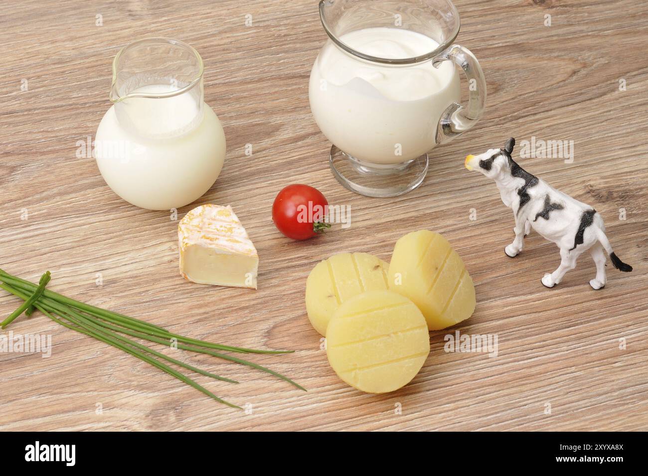 Kuh, Joghurt, Käse und Milch auf einem Holzbrett. Käse und Milch Stockfoto