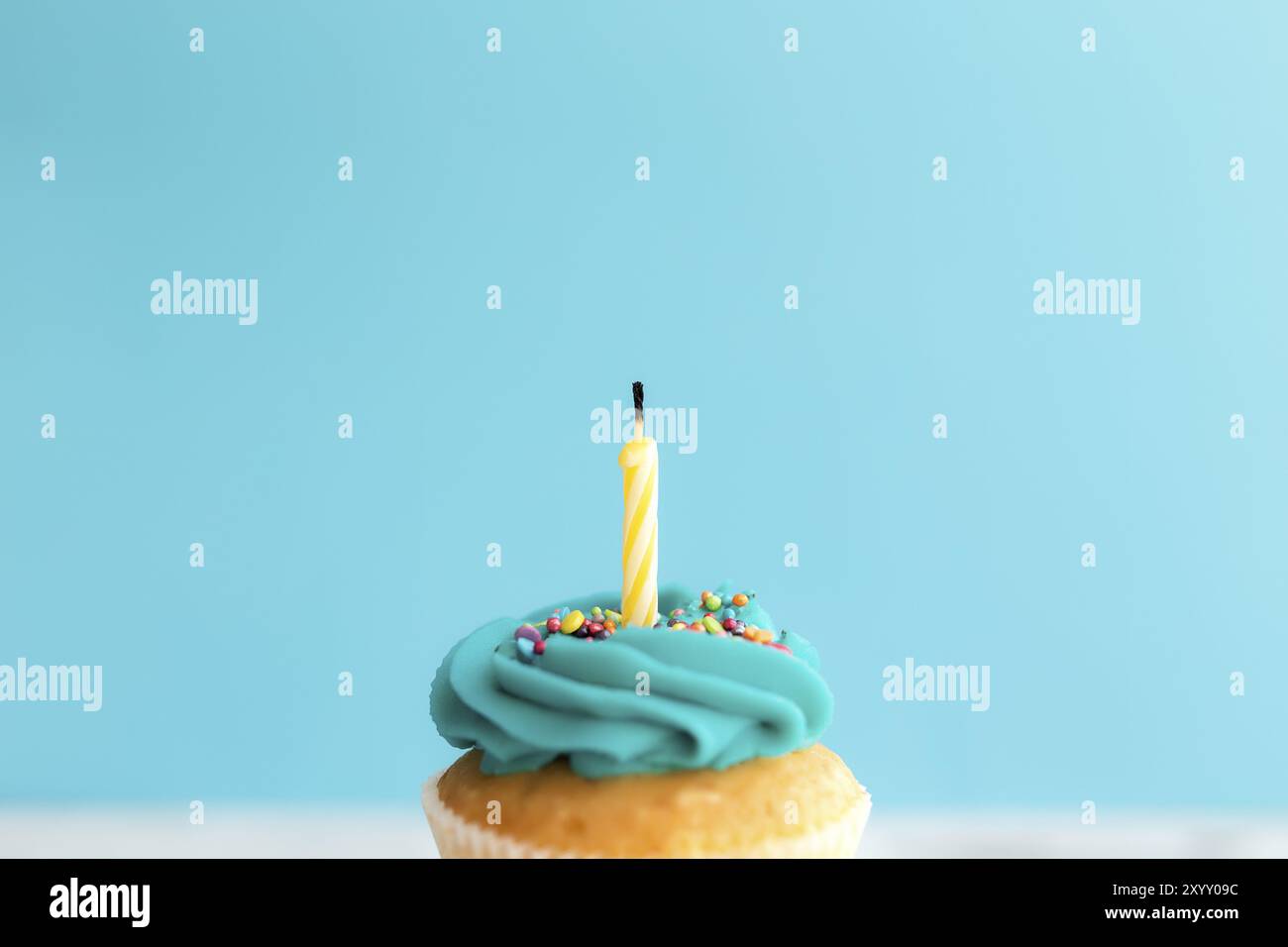 Geburtstagsgrußkonzept. Eine Kerze auf einem Muffin oder Cupcake. Blauer Hintergrund Stockfoto
