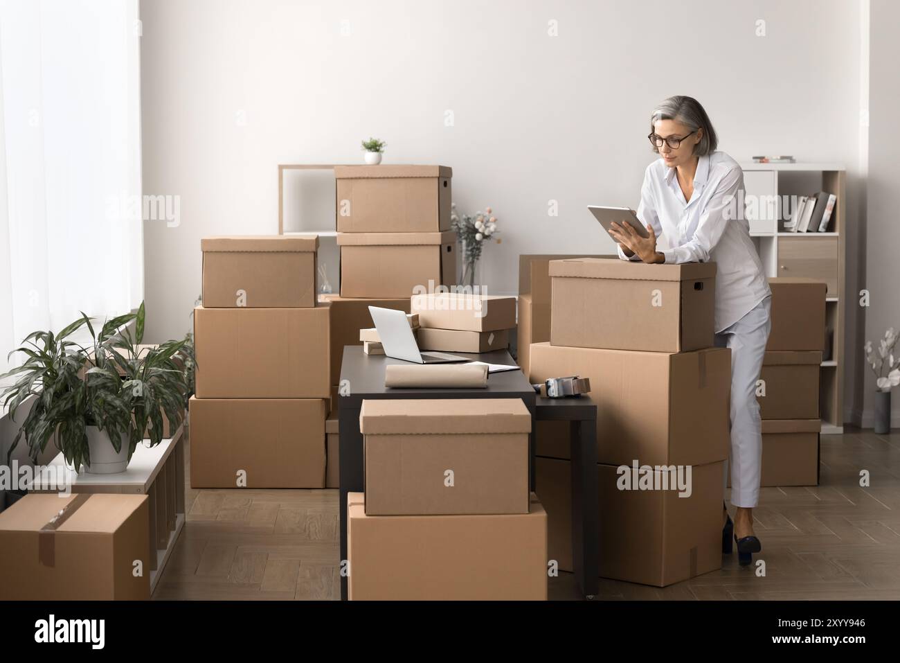 Frau, die ein Tablet verwendet, das sich mit der Verwaltung von Bestellungen und dem Workflow für Lagerbestände beschäftigt Stockfoto