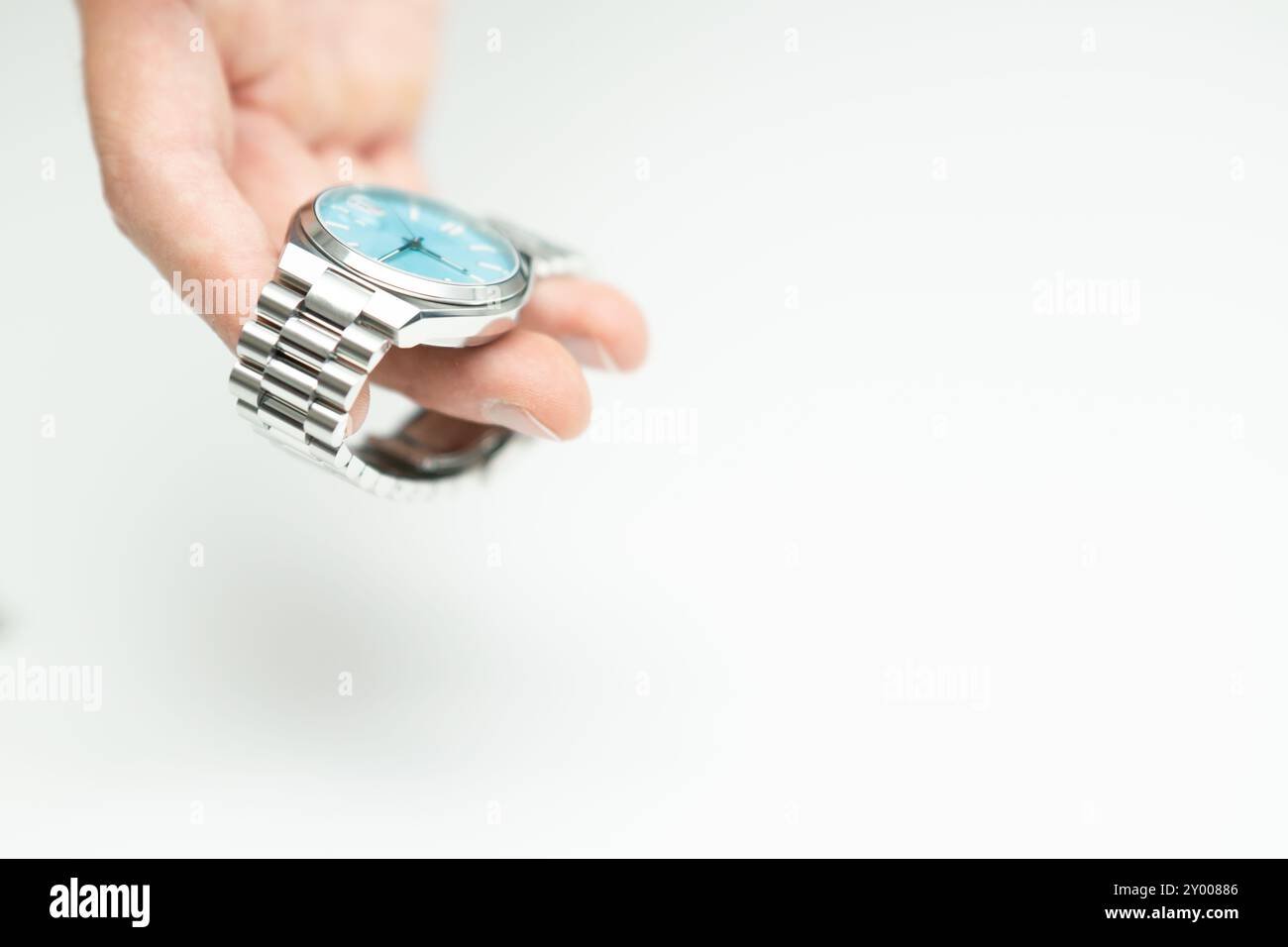 Männliche Hand, die moderne luxuriöse silberne tiffany-blaue Uhr auf weißem Hintergrund hält Stockfoto