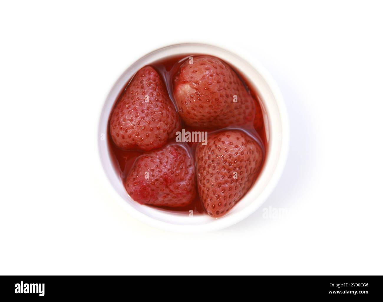 Vier Erdbeeren in ihrem eigenen Saft auf dem Teller auf weißem Hintergrund Stockfoto