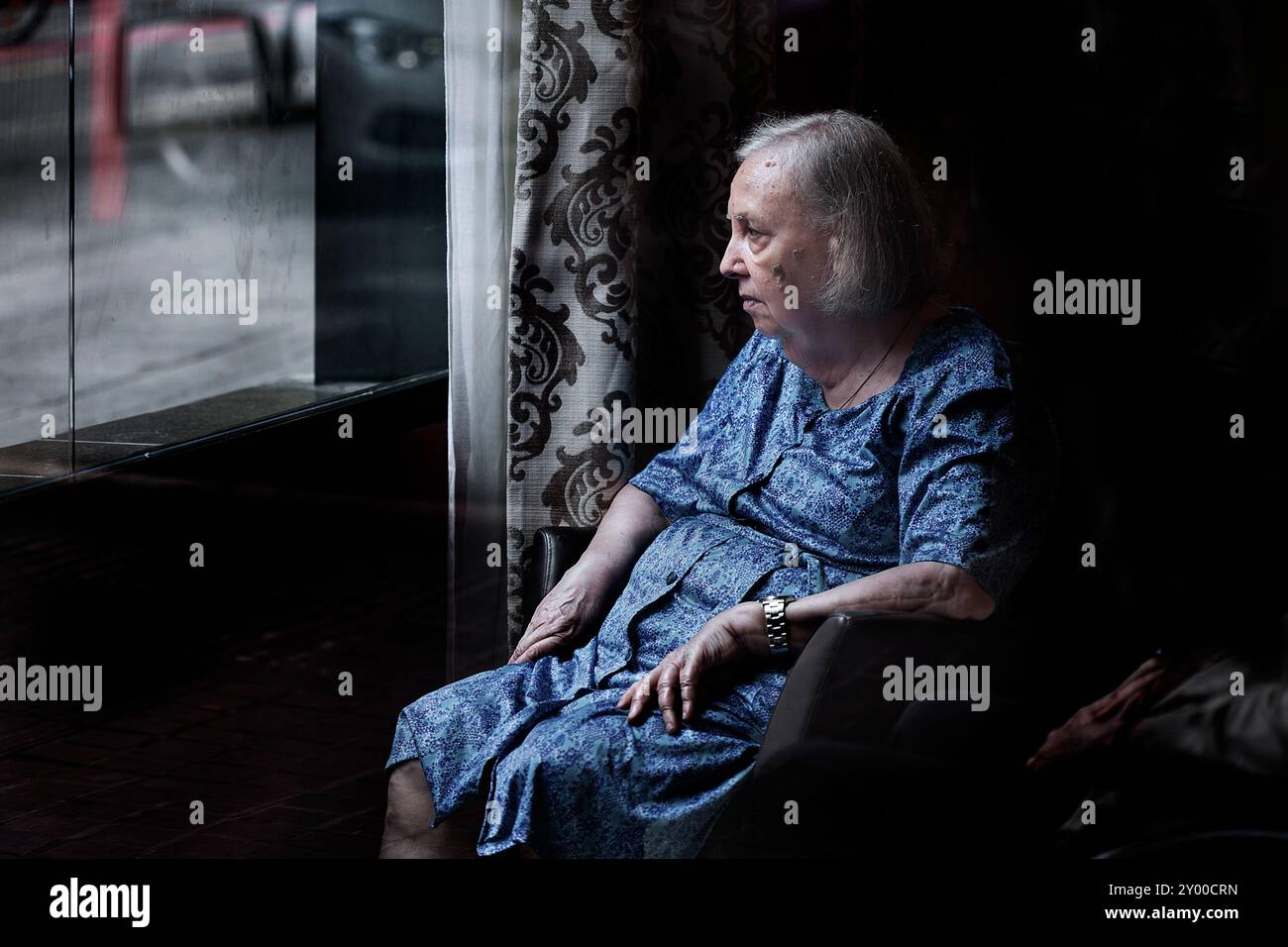 Alte Frau saß am Fenster der Residenz, Barcelona. Stockfoto