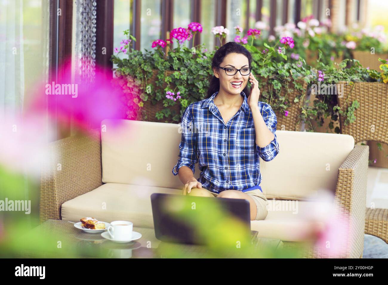 Junge Frau, die arbeitet auf Computer im freien Gespräch auf ein Mobiltelefon Stockfoto