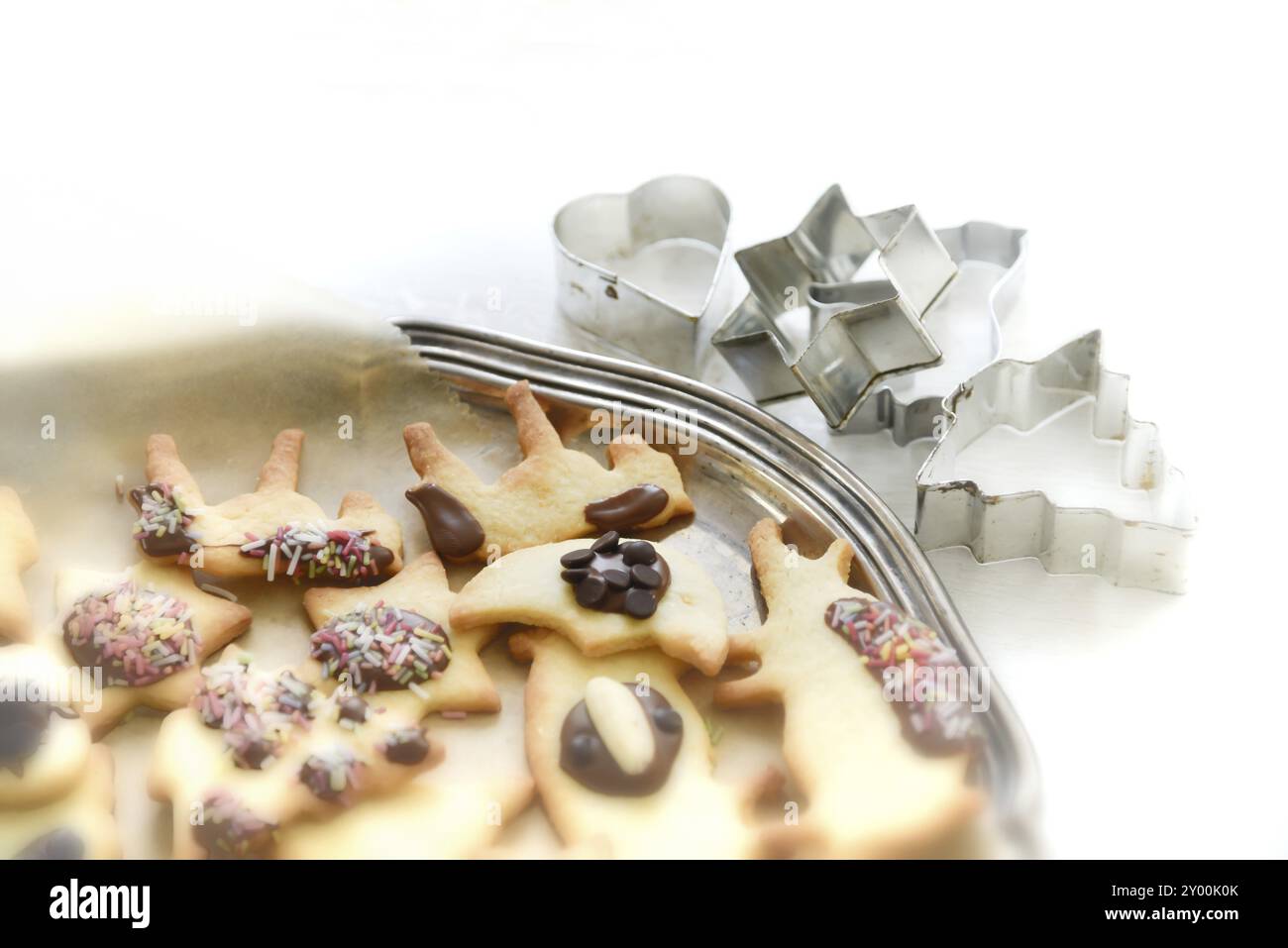 Frisch gebackene Weihnachtsgebäck auf einem antiken silbernen Tablett und Keksschneider im Hintergrund. Frisch gebackene Weihnachtsplätzchen, farbenfroh dekoriert Stockfoto