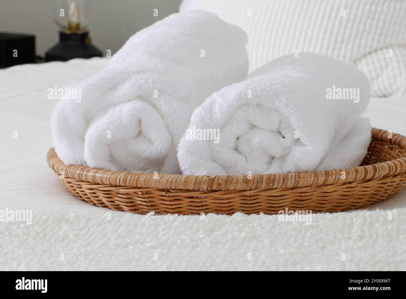 Blick auf die Betteinrichtung mit Korb und weißen Handtüchern. Stockfoto