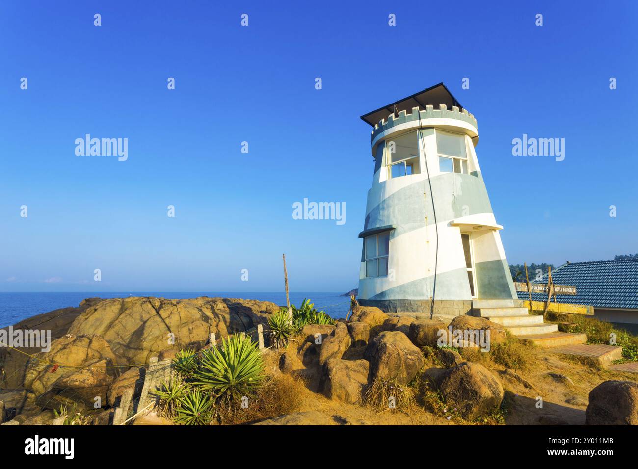 Treppen führen an einem klaren, sonnigen Morgen in Kovalam Beach, Kerala, Indien, zum Eingang des Rettungsdienstes, der einem steinigen Leuchtturm ähnelt. Horizont Stockfoto