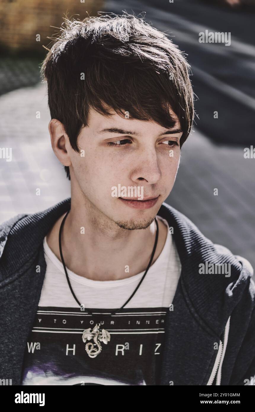 Junger erwachsener Rockmusiker, der wegschaut, Seitenansicht, Sänger trägt ein blaues Sweatshirt und T-Shirt, steht, braune Haare und Bart Stockfoto