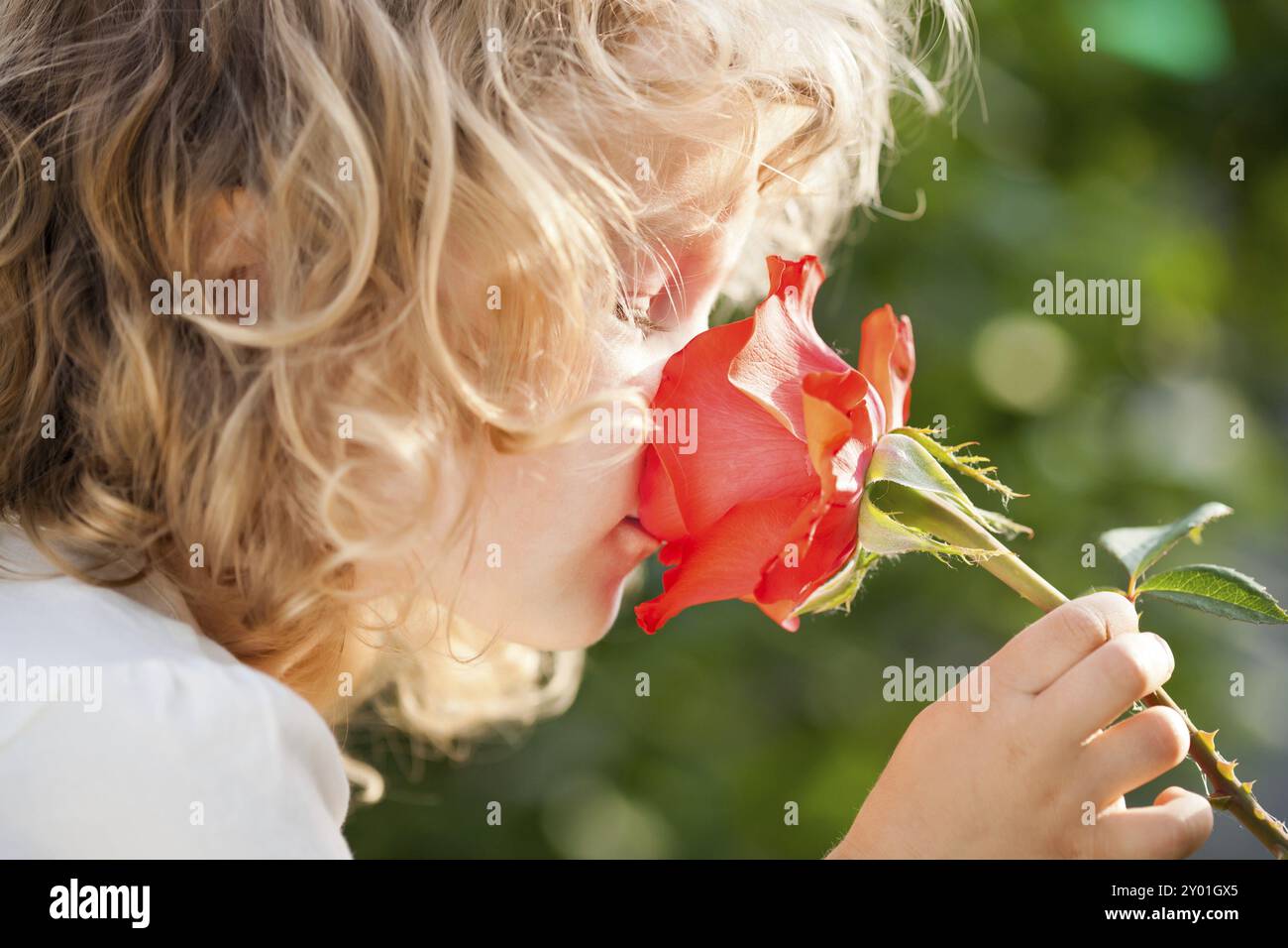 Kind mit Rosenblume im Frühlingsgarten Stockfoto