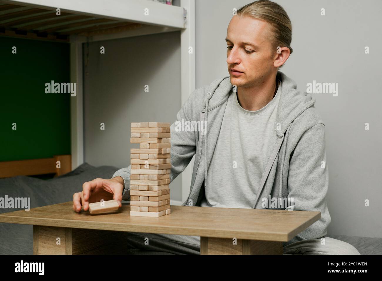 Die Person stapelt sorgfältig Blöcke in Holzturmspiel im Raum zu Hause. Digitale Detox und Konzentration. Qualitätszeit offline Stockfoto